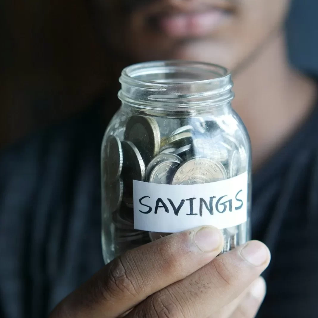 a man holding a jar with a savings label on it