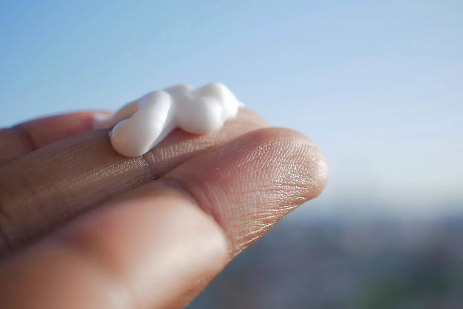 A hand holding a small piece of marshmallow