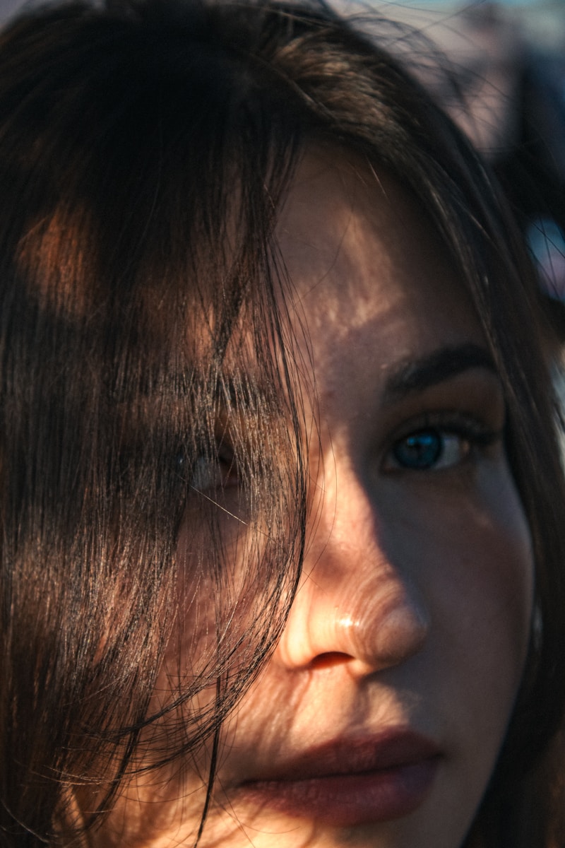 A woman's face is partially obscured by shadows.