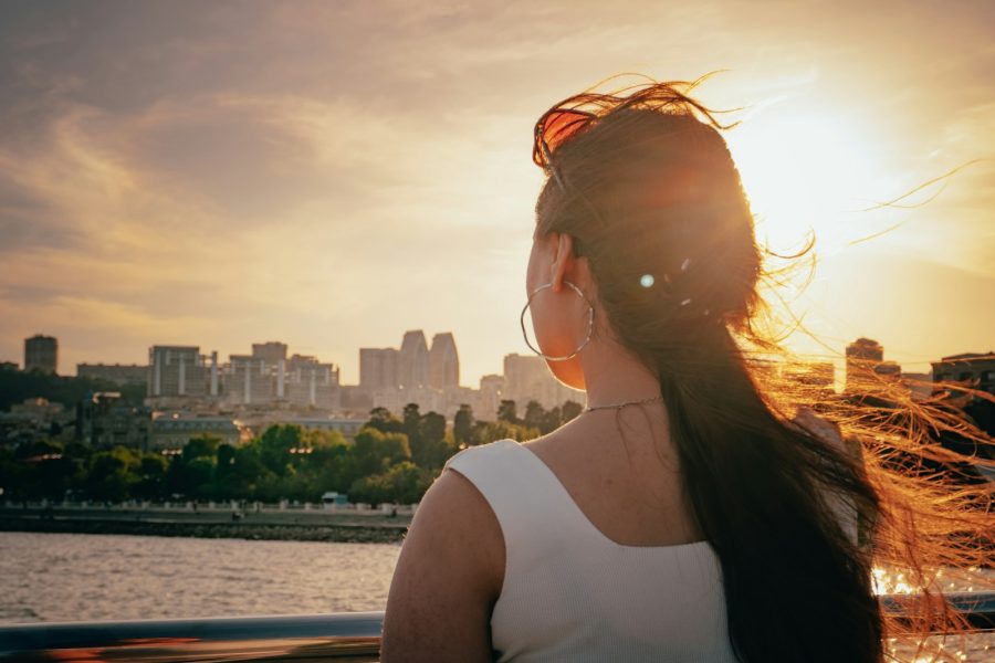 A woman looks toward a city at sunset.